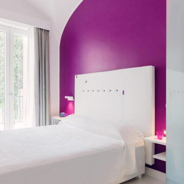 Chambre moderne du Ravello In avec lit double et mur violet.