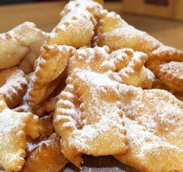 Beignets de carnaval de Sorrente saupoudrés de sucre glace sur une assiette.