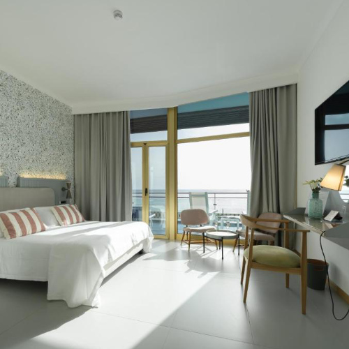 Chambre moderne et lumineuse avec grand balcon face à la mer au Reginna Palace Hotel.