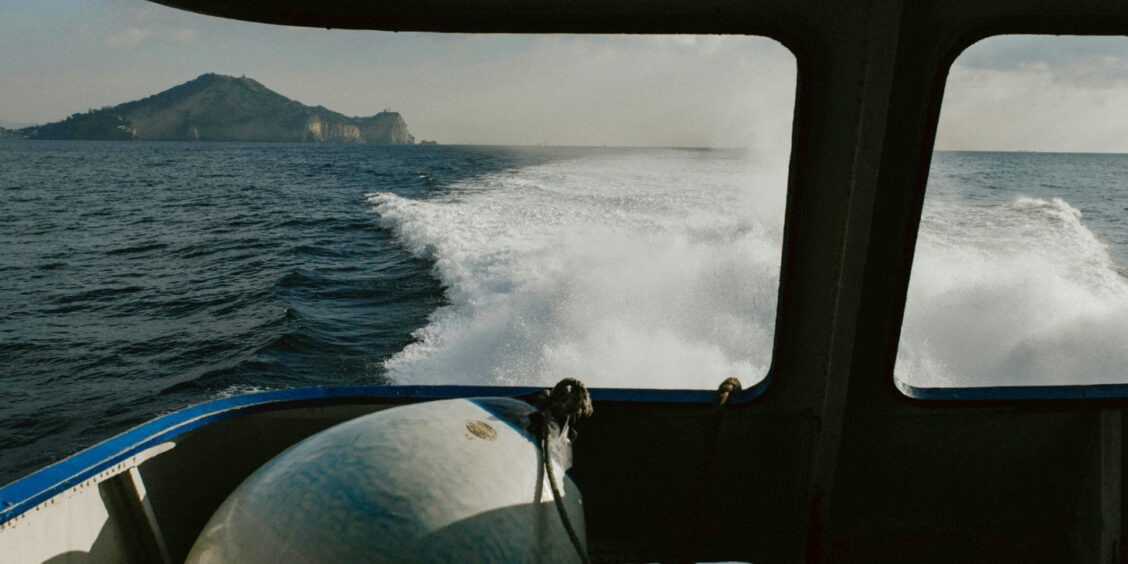 Sillage d'un ferry en mer avec une île à l'horizon.