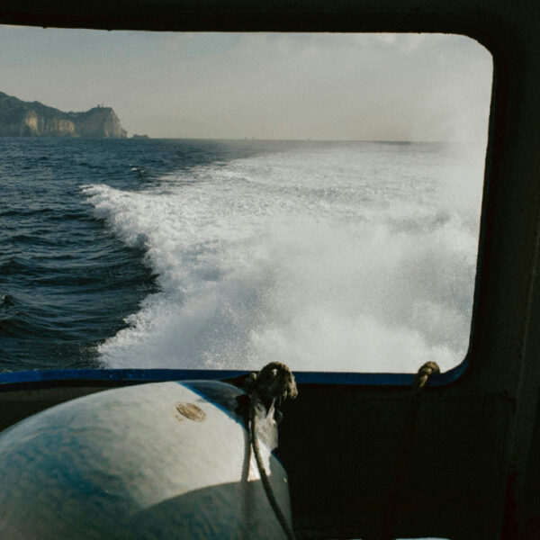 Sillage d'un ferry en mer avec une île à l'horizon.