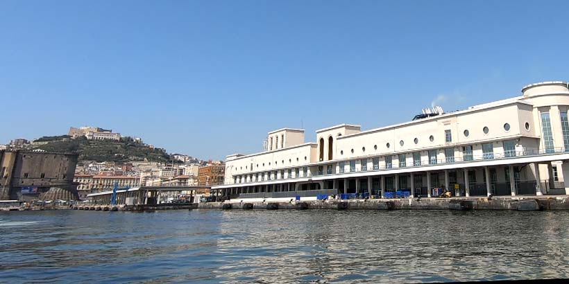 Molo Beverello à Naples avec terminal portuaire, vue sur la mer et la ville en arrière-plan.