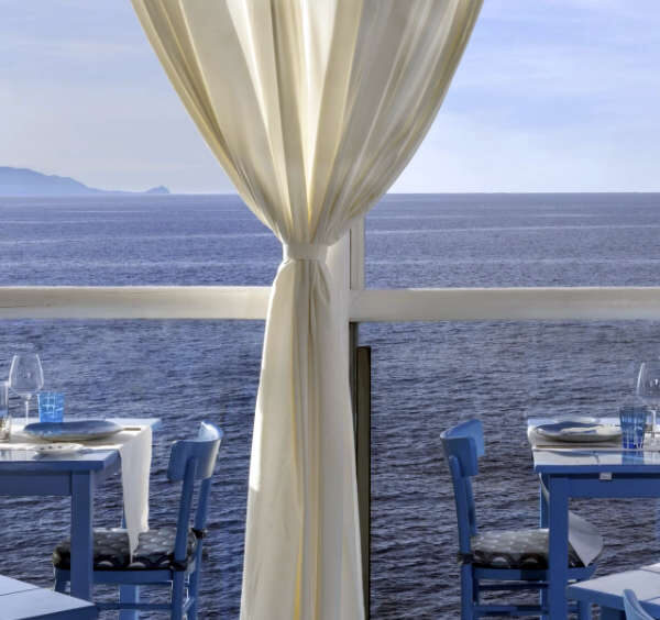 Vue sur la mer Méditerranée depuis la terrasse face à l'eau del restaurant de prestige Il Riccio à Anacapri, con des tables dressées pour un dîner d'exception.