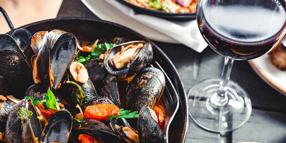Plat de moules aux tomates avec un verre de vin rouge dans un restaurant à Sorrente.