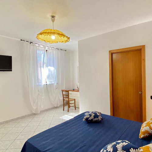 Chambre épurée avec lit bleu, bureau et décoration aux accents jaunes.