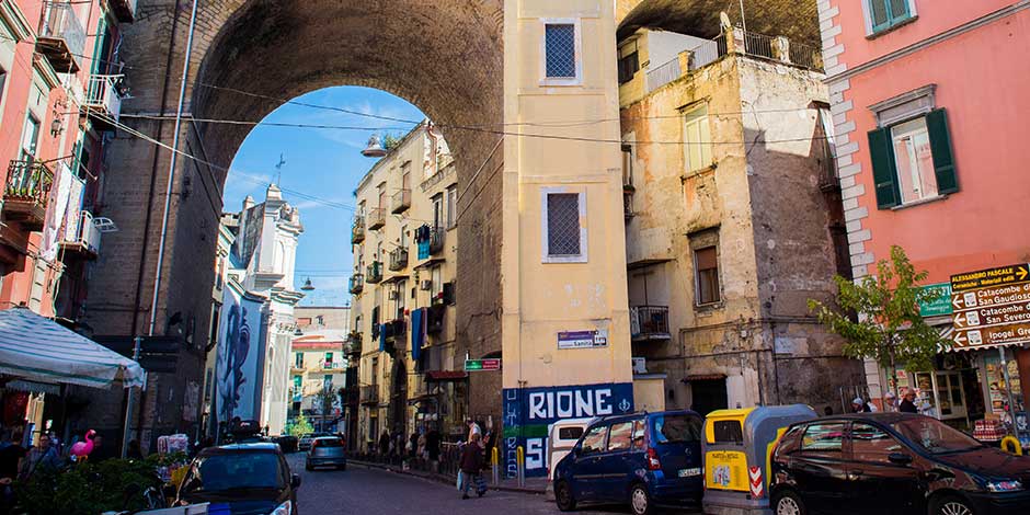 Rione Sanità à Naples avec arche urbaine et rue animée du quartier populaire historique.
