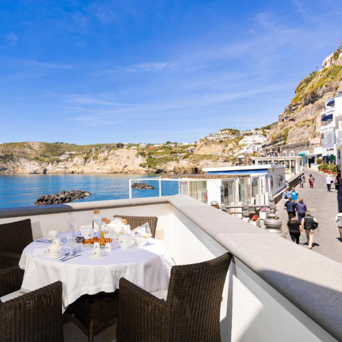 Petit-déjeuner servi en terrasse avec vue sur la mer et le village de Sant'Angelo.