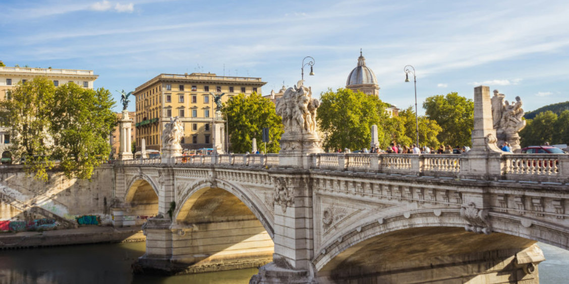 Le pont Vittorio Emanuele II orné de sculptures monumentales enjambant le Tibre à Rome, sous un ciel bleu printanier.