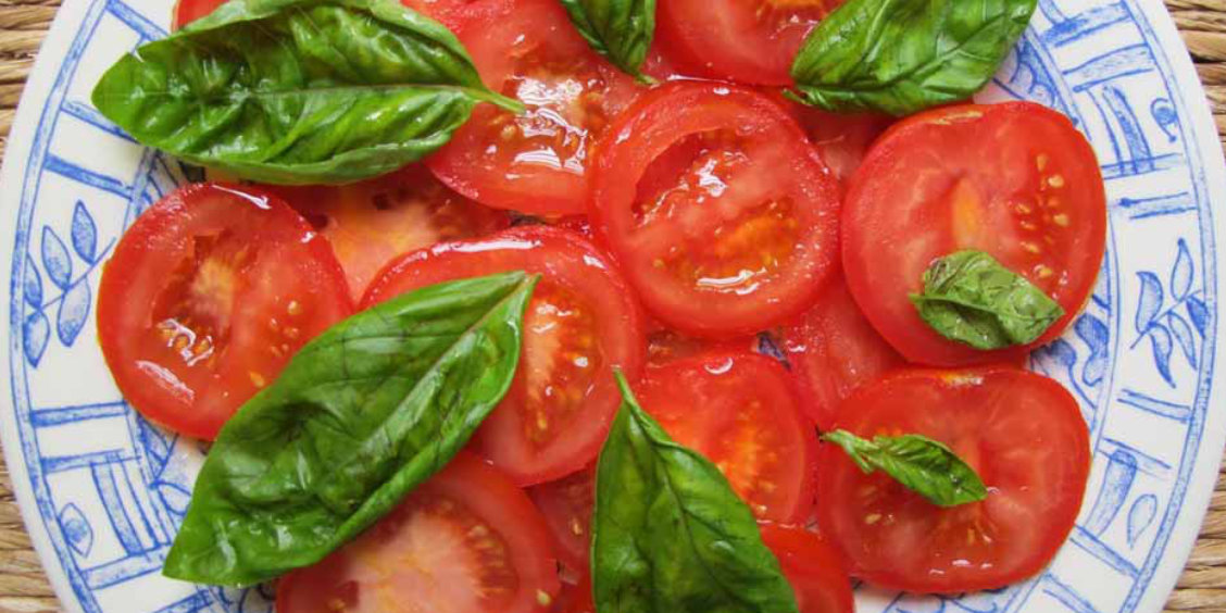 Salade de tomates napolitaines avec basilic frais et huile d’olive, spécialité italienne simple et savoureuse.