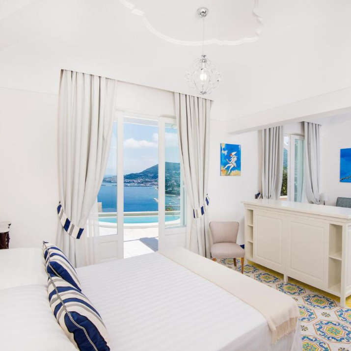 Chambre élégante aux tons bleus et blancs avec balcon vue mer au San Montano Resort & Spa.