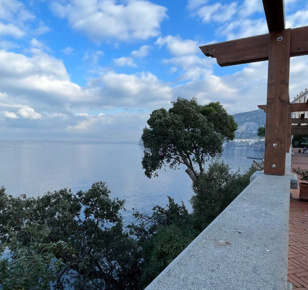 Vue sur la mer depuis Sant’Agnello, avec terrasse panoramique, arbres méditerranéens et côte de Sorrente.