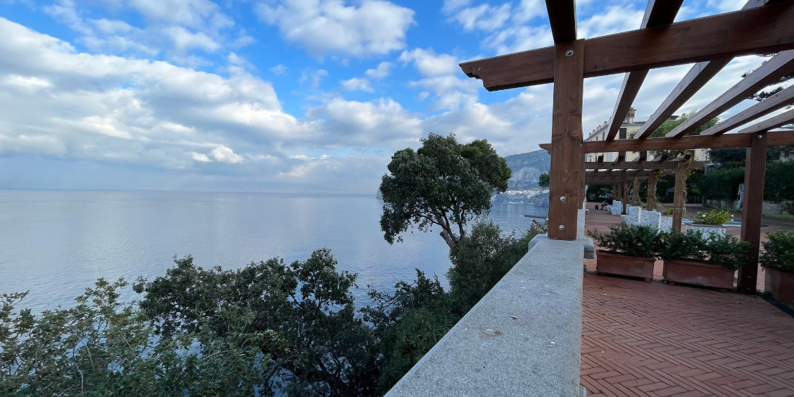 Vue sur la mer depuis Sant’Agnello, avec terrasse panoramique, arbres méditerranéens et côte de Sorrente.