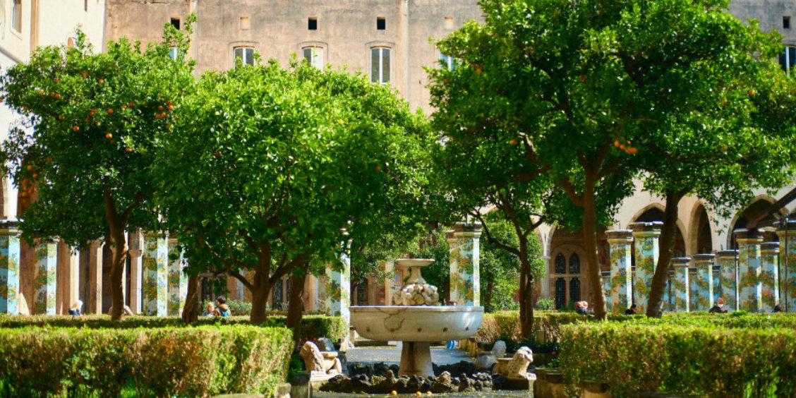 Cloître de Santa Chiara à Naples avec jardin, fontaine centrale et colonnes décorées de majolique.
