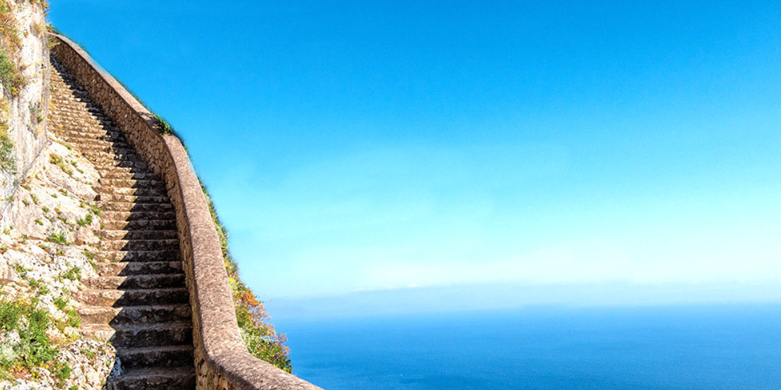 Escalier monumental de la Scala Fenicia à Capri serpentant sur le flanc de la falaise face à la mer bleue.