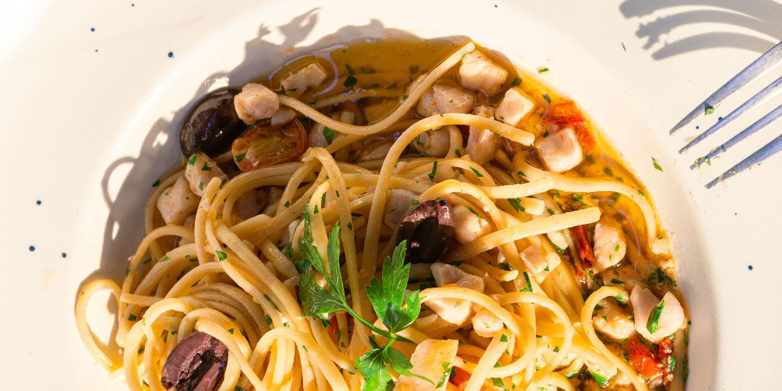 Assiette de scialatielli aux fruits de mer et olives sur une table traditionnelle à Amalfi.