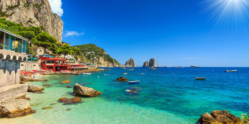 Eaux turquoise cristallines et rochers Faraglioni sous un soleil éclatant sur la côte de Capri.