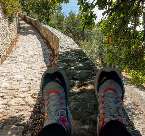 Sentier piéton à Sorrente avec chaussures de randonnée, murs en pierre et oliviers.
