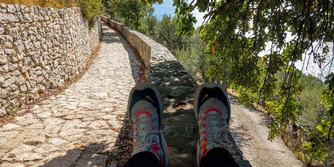 Sentier piéton à Sorrente avec chaussures de randonnée, murs en pierre et oliviers.