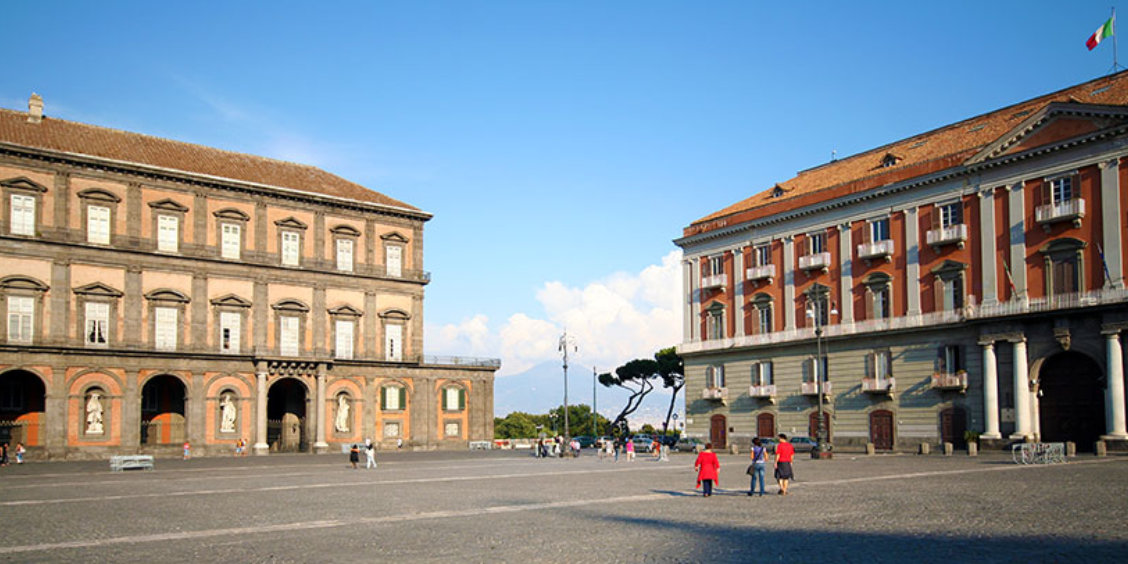 Place du Plébiscite à Naples avec le Palais Royal et bâtiments historiques sous un ciel dégagé.
