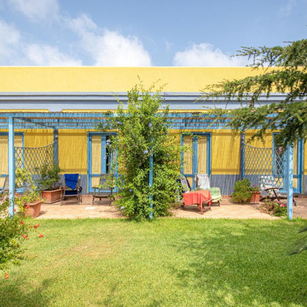 Façade colorée de la résidence avec terrasses privatives et jardin verdoyant.