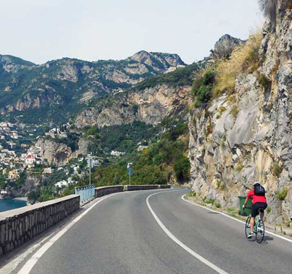Balade à vélo sur la Côte Amalfitaine avec cyclistes, falaises et vue sur Positano.