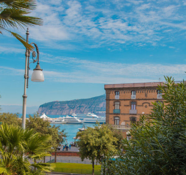 Sorrente en mars avec palmiers, port, ferry et vue sur la côte.