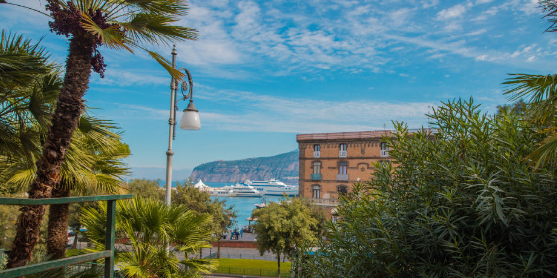 Sorrente en mars avec palmiers, port, ferry et vue sur la côte.