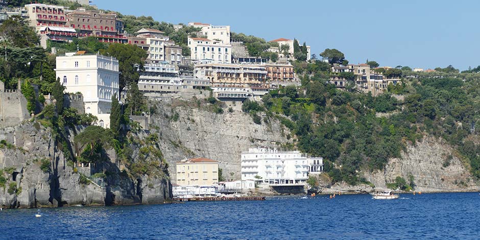 Côte de Sorrente en août avec hôtels sur les falaises et mer bleue.