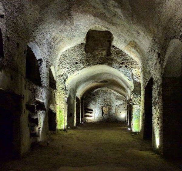 Souterrains de Naples avec galeries voûtées en pierre et passages historiques éclairés.