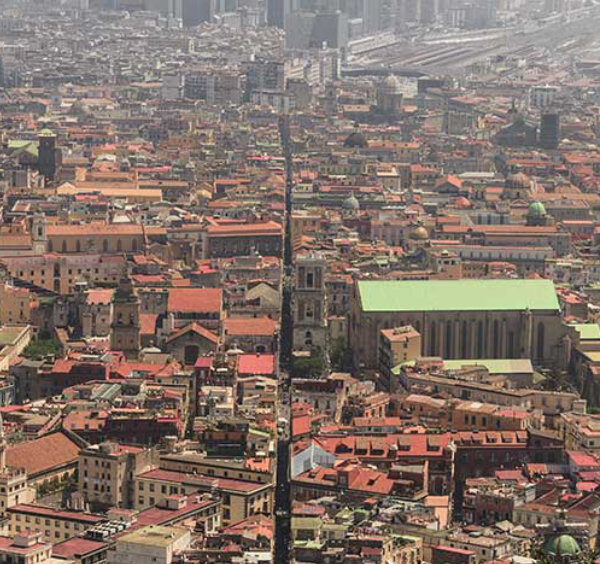 Vue aérienne de Naples montrant la célèbre rue Spaccanapoli fendant le centre historique et ses toits de tuiles rouges.