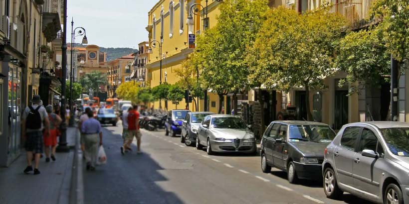 Rue de Sorrente avec voitures stationnées, piétons et bâtiments colorés.