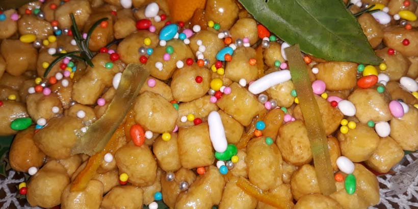 Struffoli napolitains : petites boules de pâte frites enrobées de miel et décorées de perles de sucre colorées.