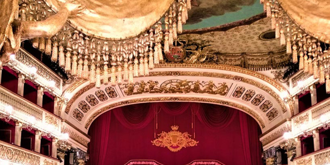 Intérieur du théâtre San Carlo à Naples avec scène, rideau rouge et décorations dorées.