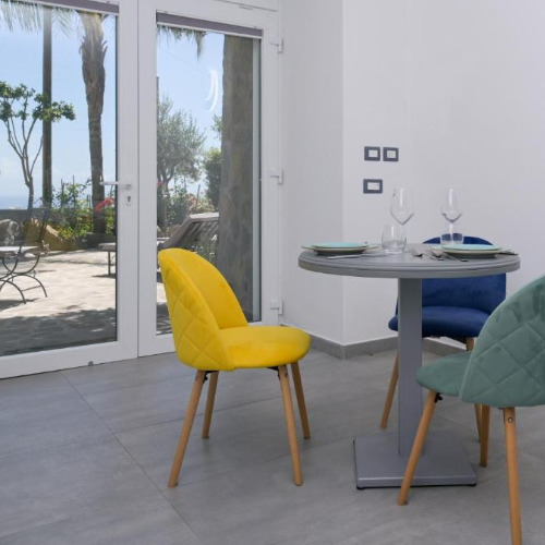 Espace repas lumineux avec chaises colorées et accès terrasse à la Tenuta Monte di Panza.