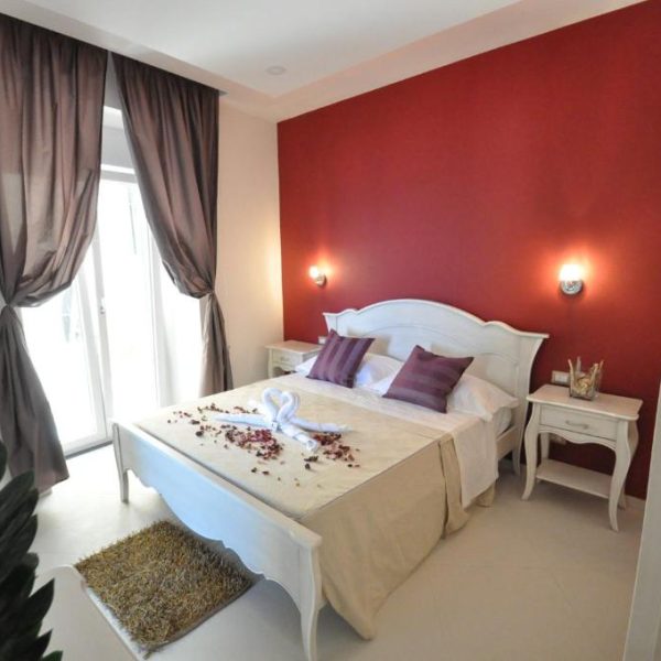 Chambre élégante avec mur rouge au Terra Murata Boutique B&B à Procida, confort et style sur l'île de Campanie.