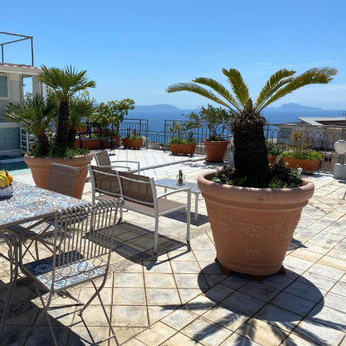 Grande terrasse panoramique sur le toit à Naples avec table en céramique et vue sur Capri.