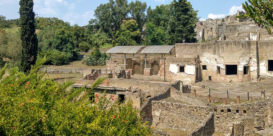 Vue panoramique des ruines des thermes suburbains de Pompéi entourées de verdure.