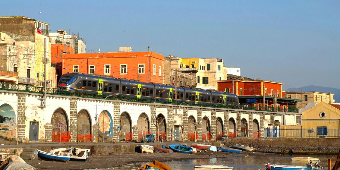 Train sur un viaduc surplombant le port et les maisons colorées de Torre Annunziata.