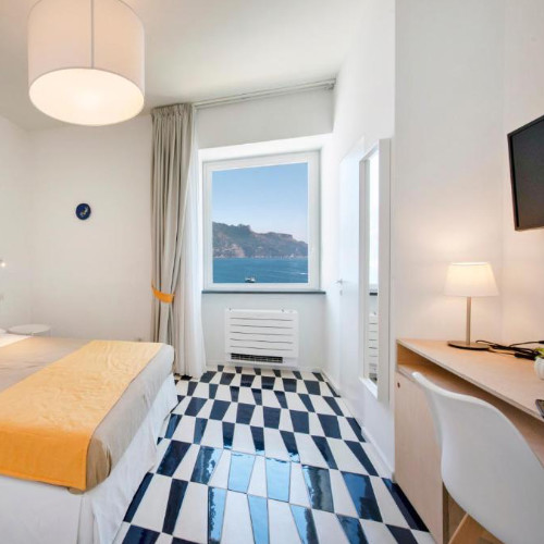 Chambre moderne avec sol en faïence géométrique bleue et blanche et fenêtre vue sur mer.