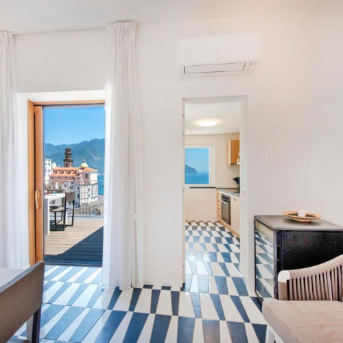 Intérieur lumineux montrant le sol en mosaïque et l'accès à la terrasse avec vue sur la côte.