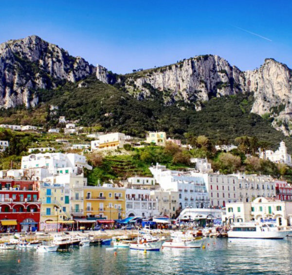 Port de Marina Grande à Capri avec ses maisons colorées, ses bateaux et ses hautes falaises rocheuses.