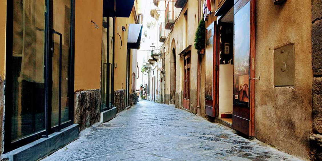 Via Pietà à Sorrente avec ruelle pavée, façades anciennes et boutiques du centre historique.