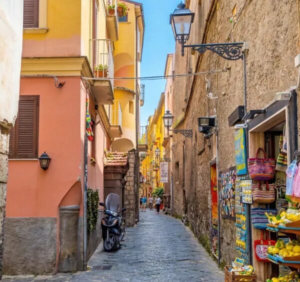 Ruelle commerçante de la via San Cesareo à Sorrente avec souvenirs, citrons et maisons colorées.