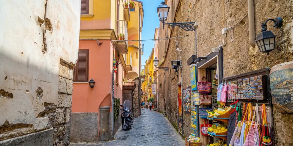 Ruelle commerçante de la via San Cesareo à Sorrente avec souvenirs, citrons et maisons colorées.