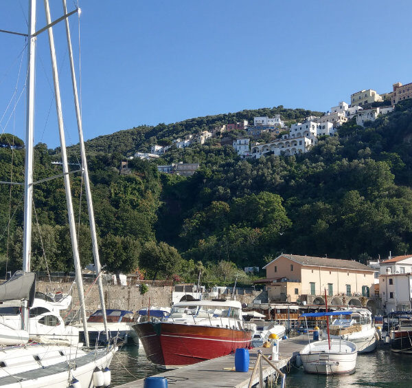 Vue du port de Vico Equense avec les bateaux, la mer et le village perché sur la côte de Sorrente.