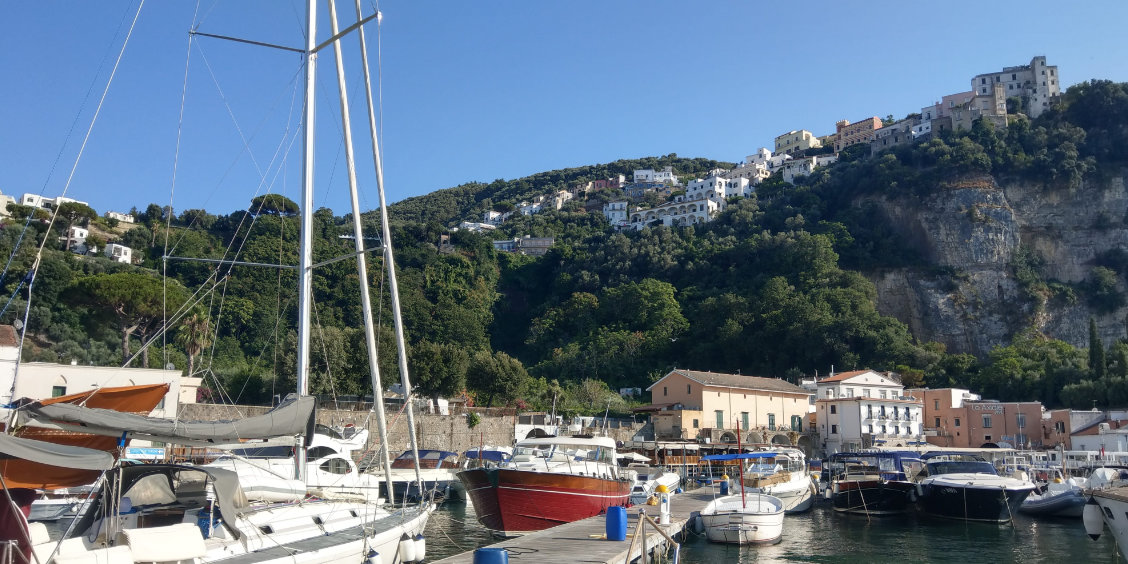 Vue du port de Vico Equense avec les bateaux, la mer et le village perché sur la côte de Sorrente.