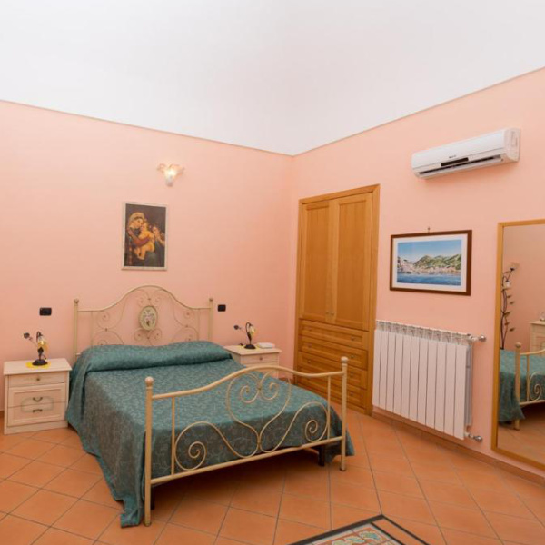 Chambre confortable de la Villa Anna avec lit en fer forgé et décoration typique de la région.