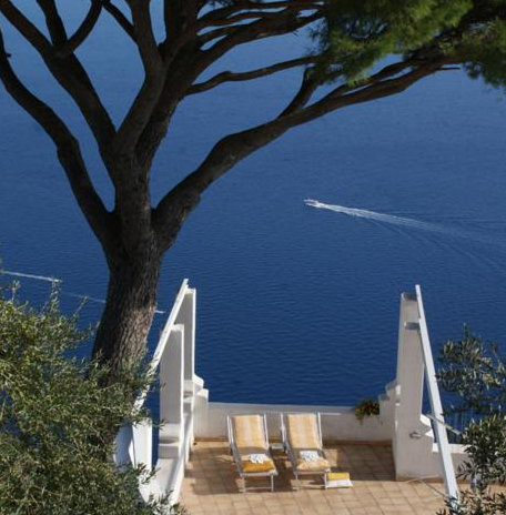 Terrasse de la Villa Aramara à Furore avec transats et vue plongeante sur la mer.