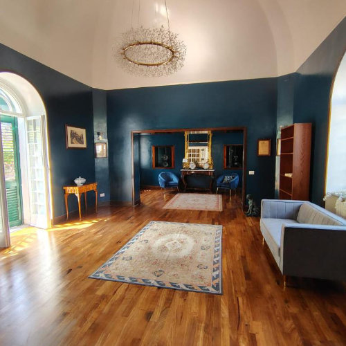 Vaste salon majestueux avec des murs bleu profond, un parquet en bois brillant, des tapis orientaux et un lustre design circulaire.
