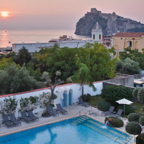 Piscine extérieure de la Villa Durelli avec vue imprenable sur le Château Aragonais au coucher du soleil.